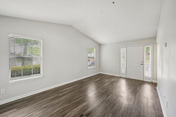 A room with wooden flooring and a window with blinds.